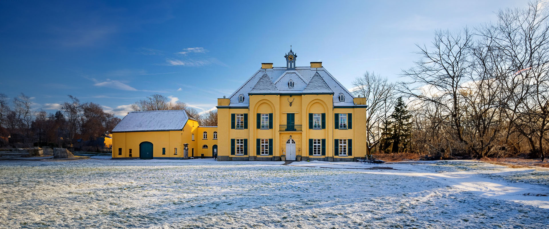 Gelbes Barockgebäude im Schnee, blauer Himmel, freistehend, künstlerische Winterlandschaft.