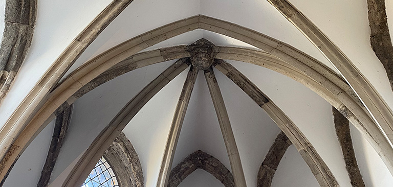 Gotisches Gewölbe mit Spitzbögen, weiß und steinfarben, kunstvolle Architektur.
