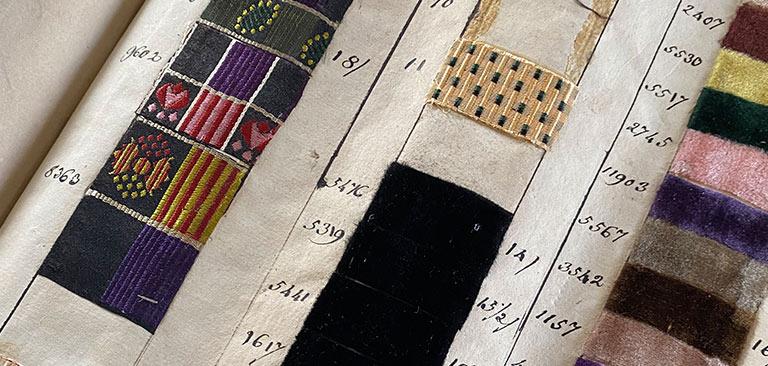Stoffmusterbuch mit verschiedenen bunten Stoffproben, handschriftlich nummeriert.